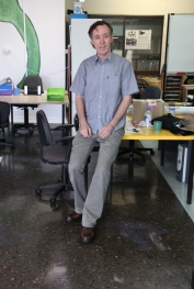 The charity's director smiling at his desk after the decorative epoxy flooring project had been completed.