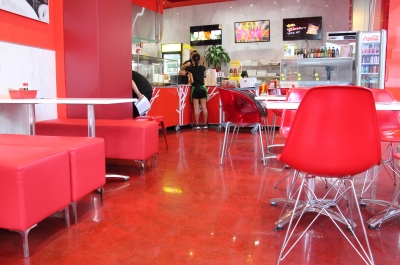 A waitress collecting an order in the food outlet with the vibrant red decorative epoxy floor in the foreground.