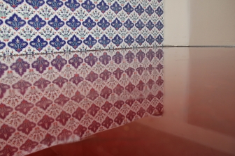 A close up of the vibrant red decorative epoxy floor showing the glossy finish through the reflection of the wall tiles.