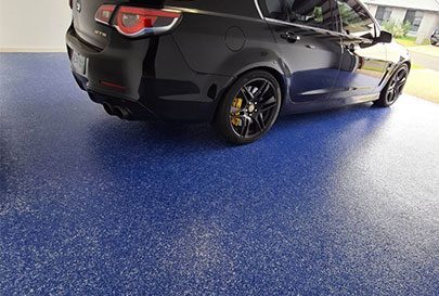 A blue epoxy garage flooring with a car parked on top.
